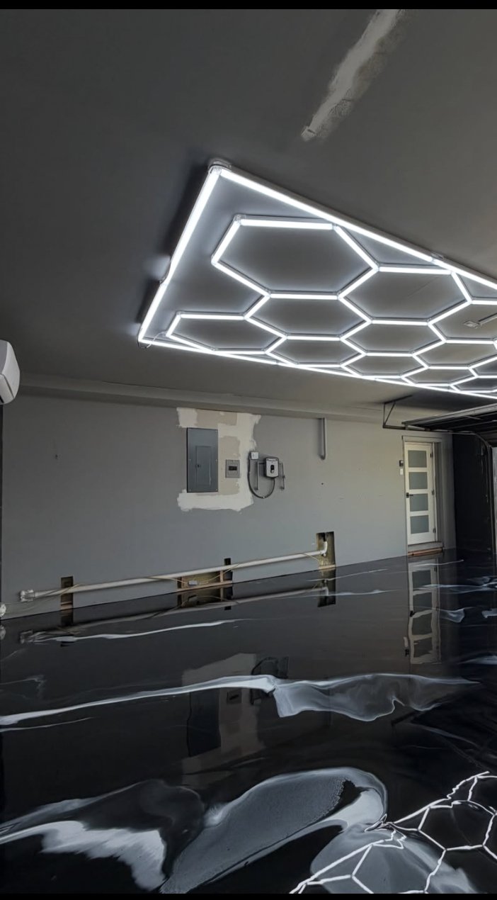 Black metallic epoxy garage floor with a mirror gloss under hex lighting