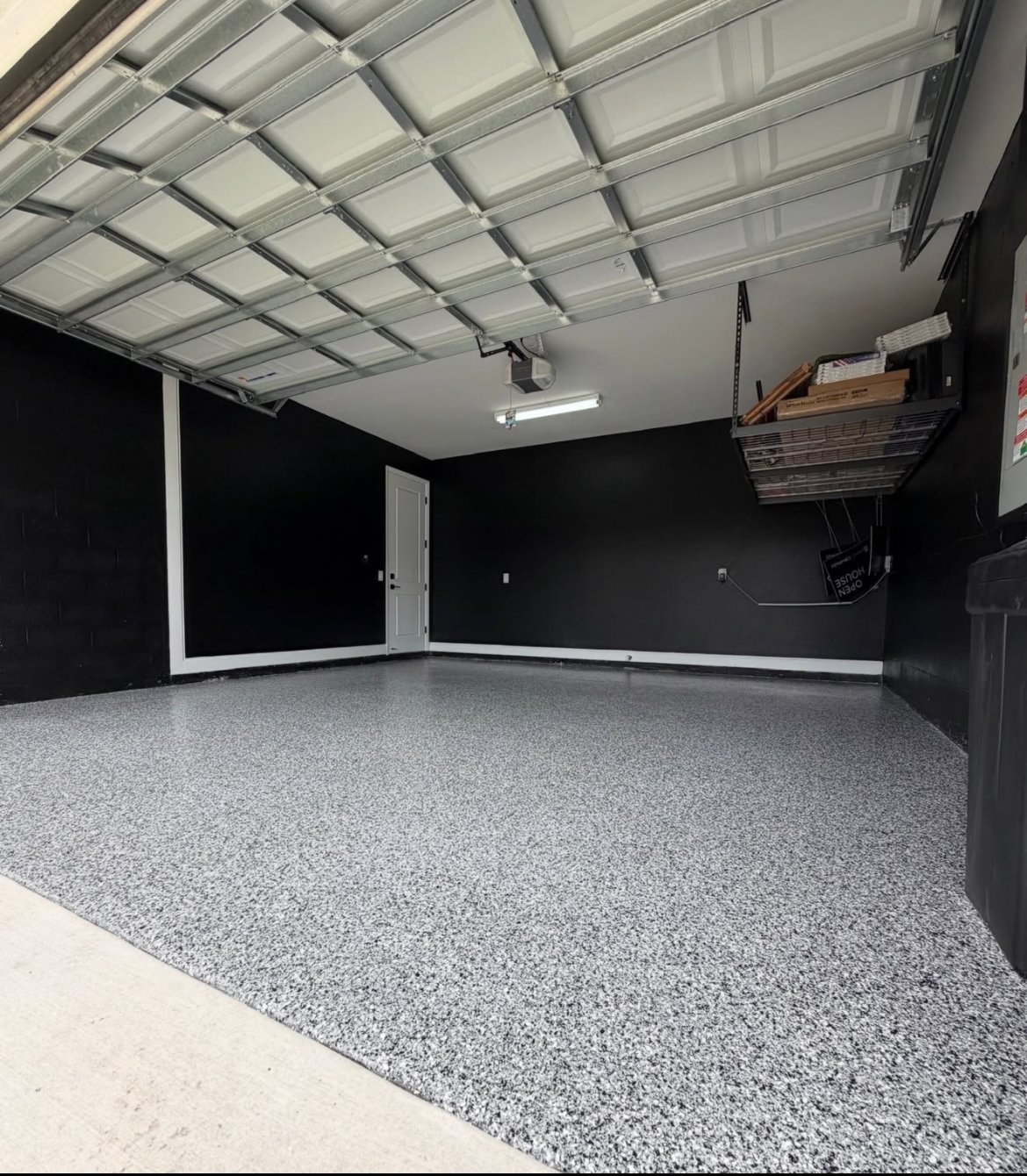 Grey flake epoxy garage floor with black-painted walls and white trim