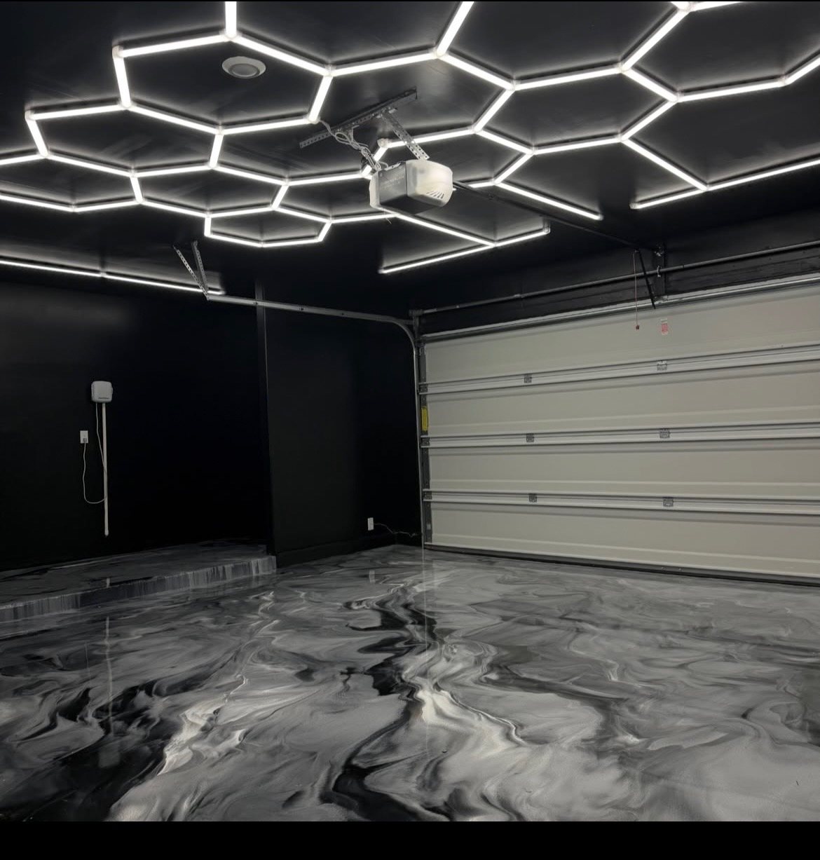 Black and charcoal metallic epoxy garage floor under a hexagon LED light grid