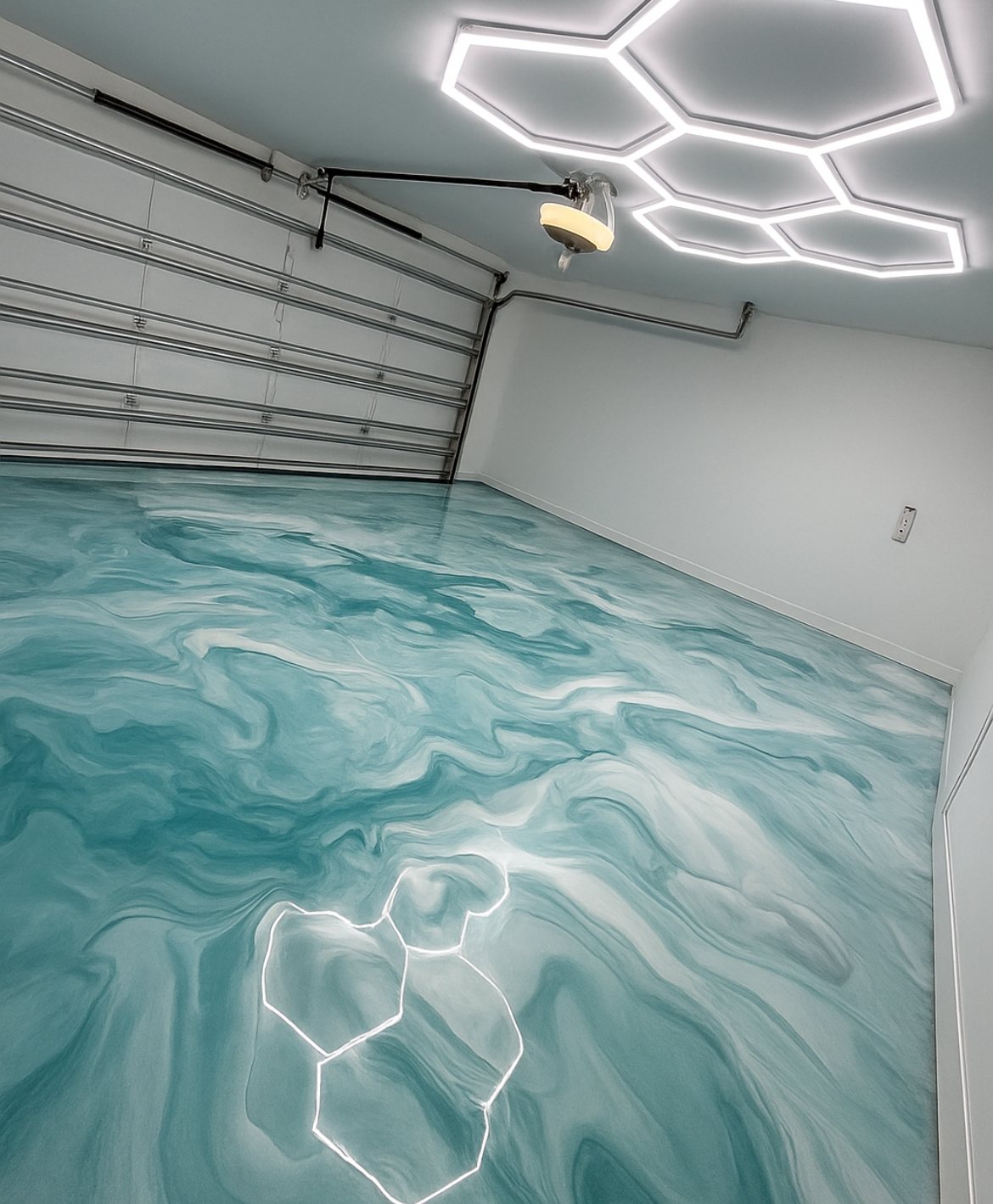 Aqua and white metallic epoxy garage floor under hexagon LED lighting