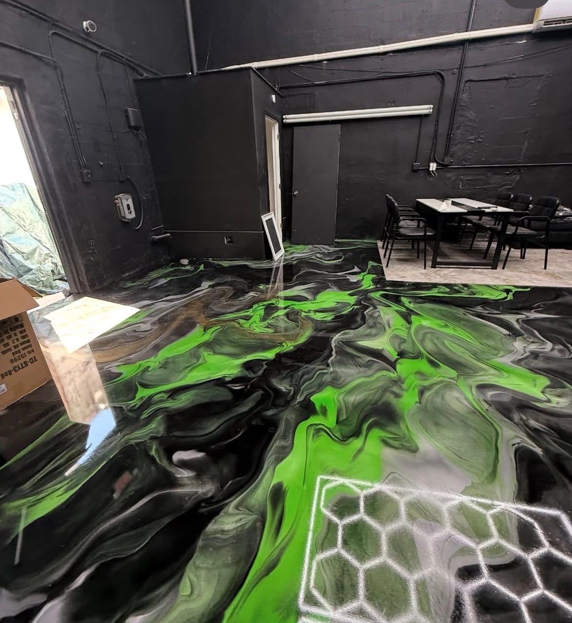 Black and green metallic epoxy floor with a hex pattern accent