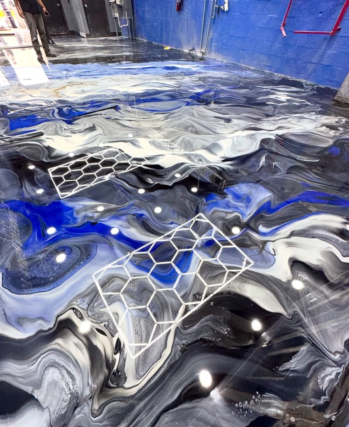 Blue and black metallic epoxy floor with a hex pattern accent