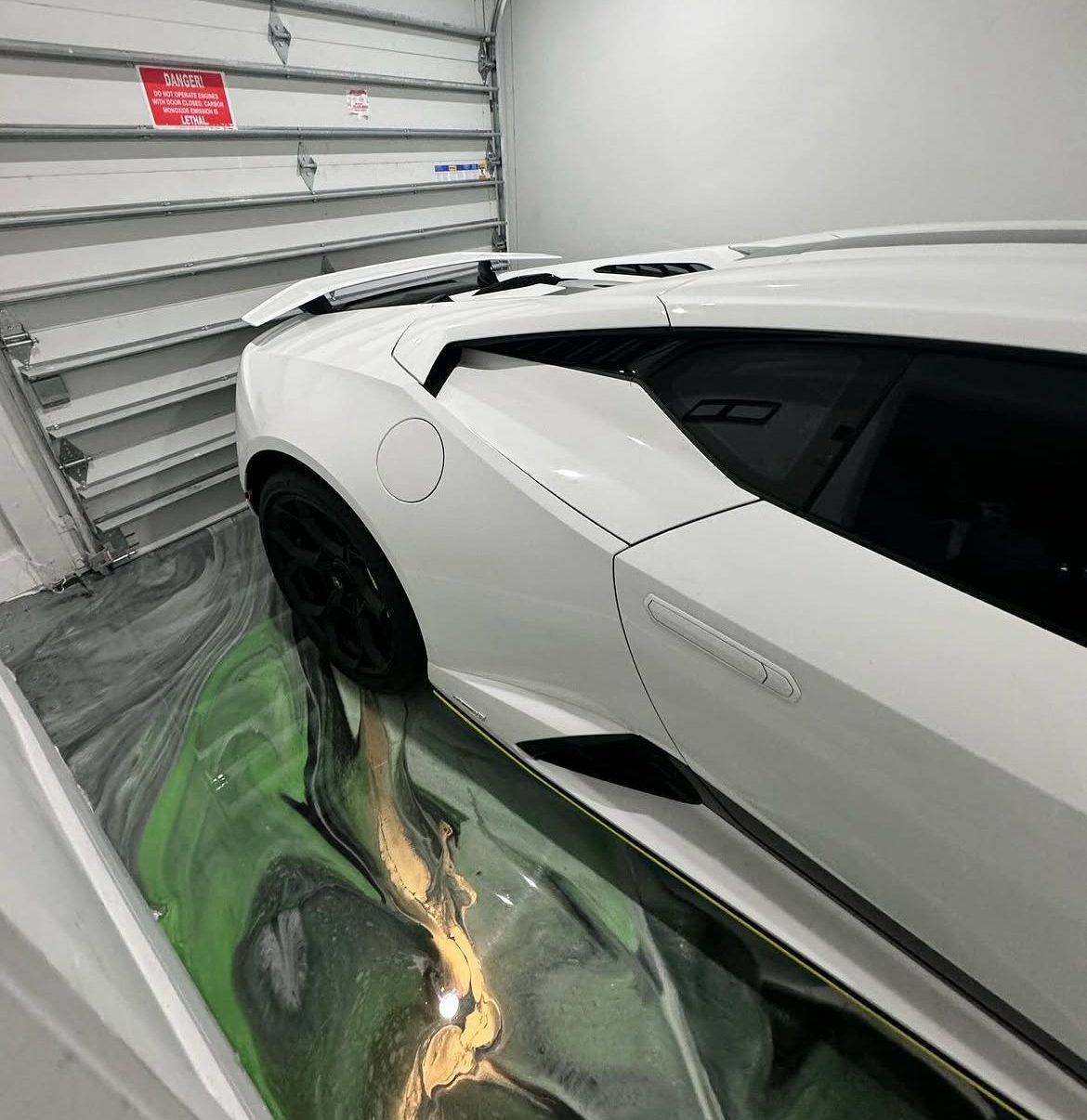Metallic epoxy garage floor running wall to wall with the bay door open