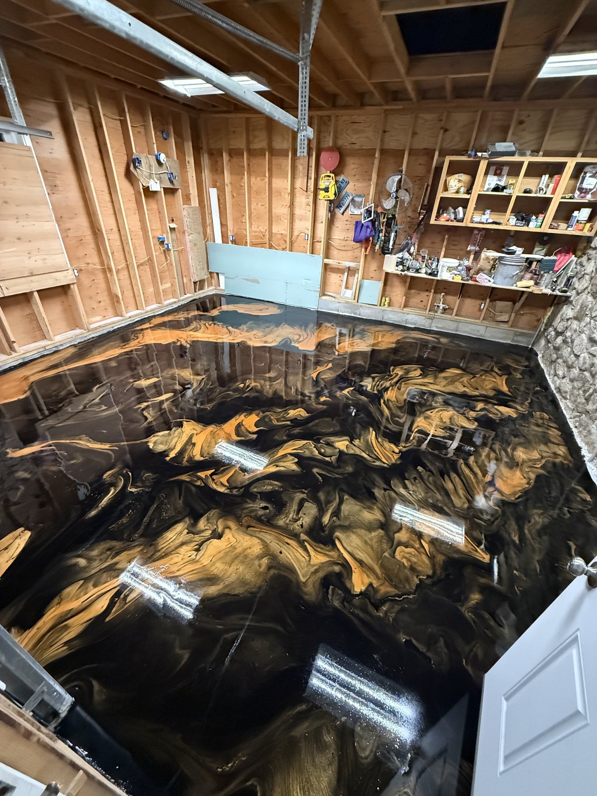 Gold and black metallic epoxy floor across a finished basement