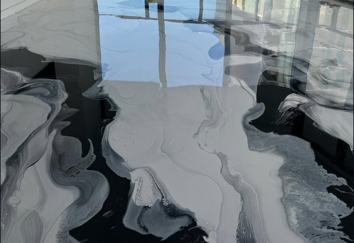 Pearl-white metallic epoxy floor with charcoal rivers in a living space with floor-to-ceiling windows